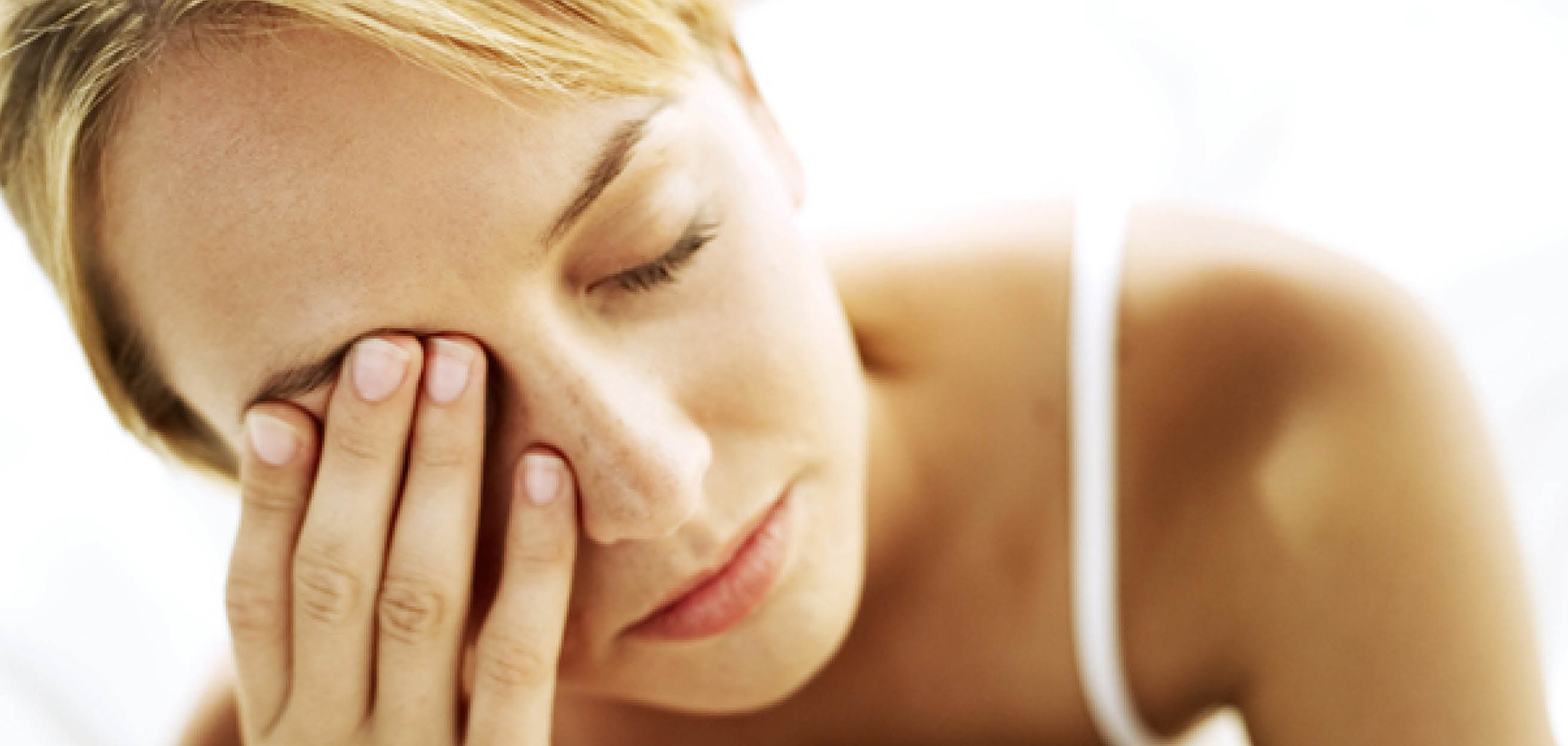 A woman rubbing her eyes and appearing very fatigued or tired